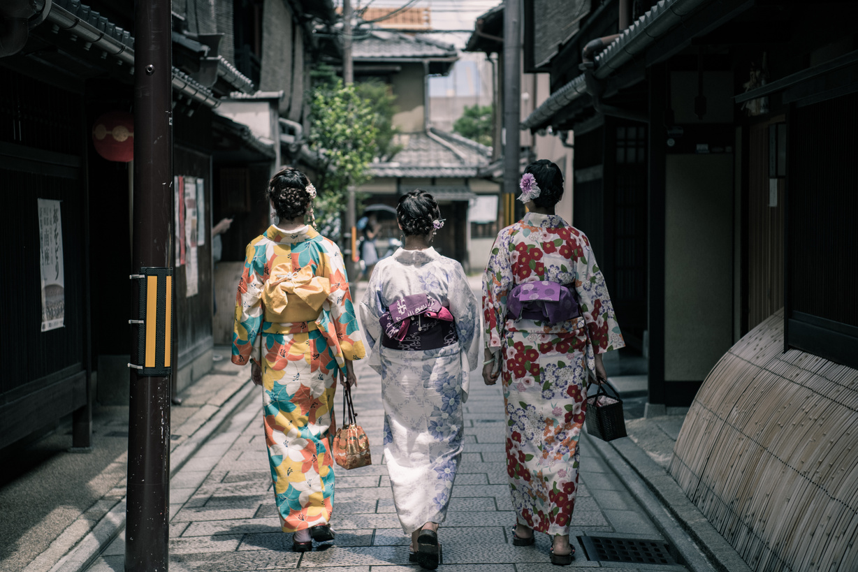 Three Geisha Walking Between Buildings